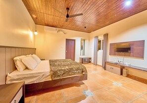 A bedroom with a bed, a TV, a ceiling fan, and a tiled floor. - Whispering Hills Attappadi by VOYE HOMES (Mannarkkad)