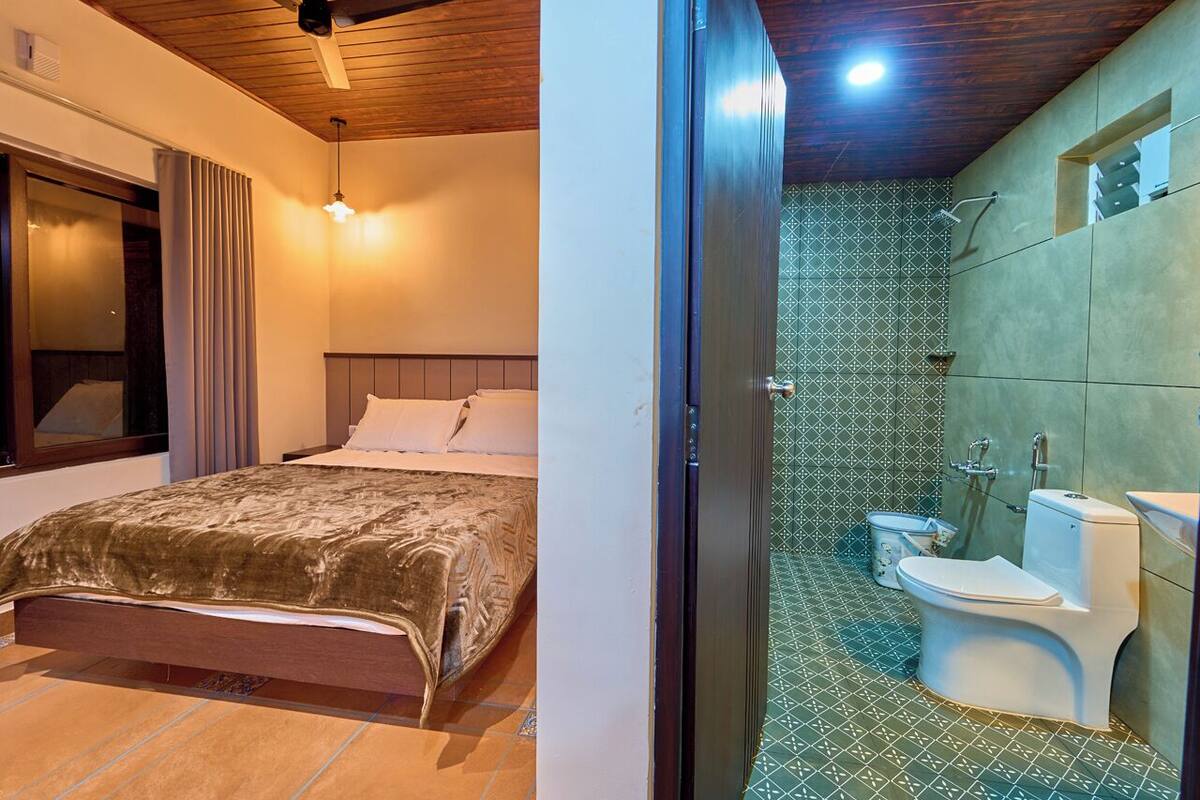 Quarto com uma cama e banheiro com vaso sanitário e chuveiro.