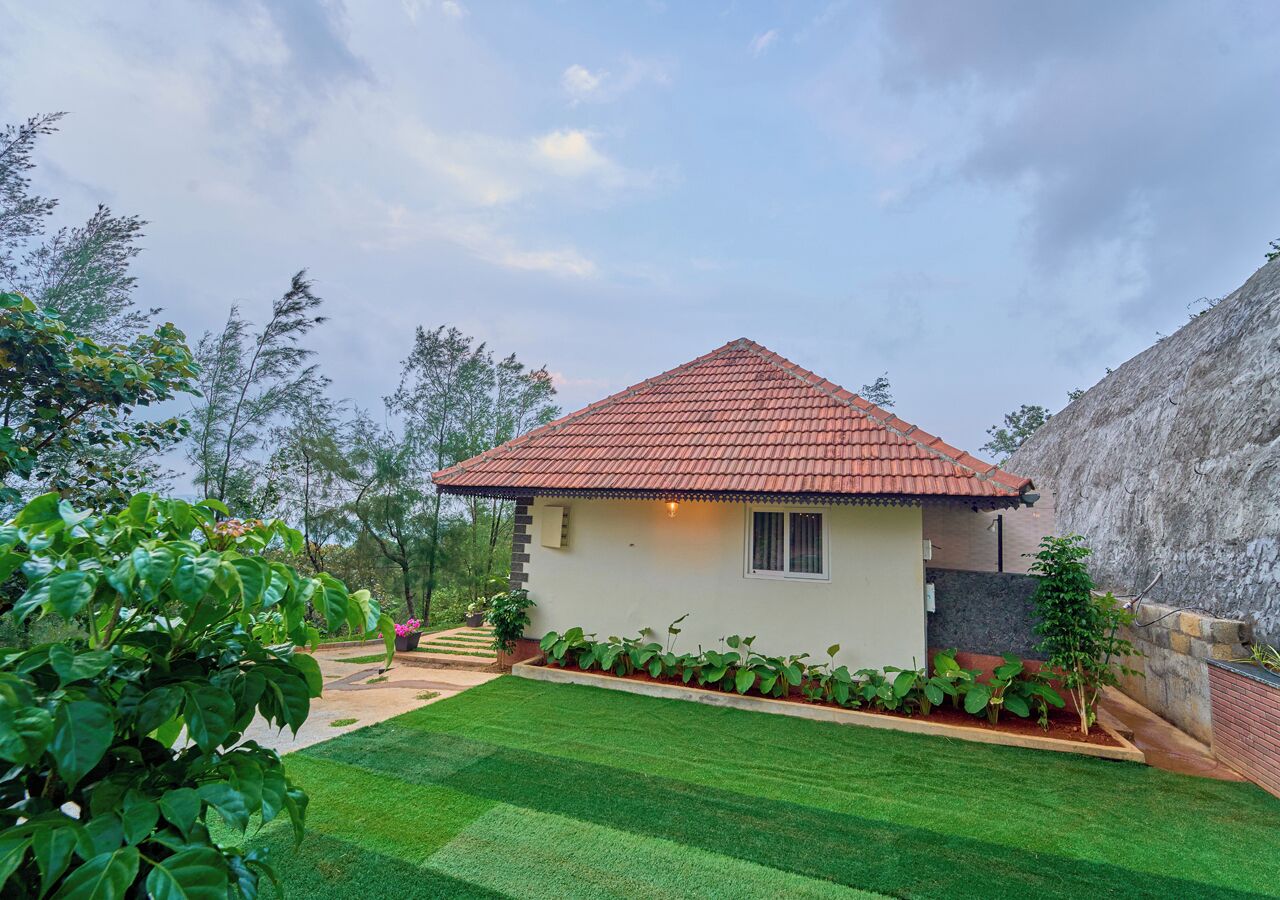 A single-story house with a red-tiled roof, surrounded by a well-maintained lawn and various plants.