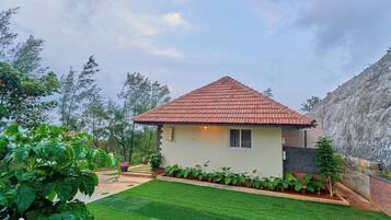 A single-story house with a red-tiled roof, surrounded by a well-maintained lawn and various plants.