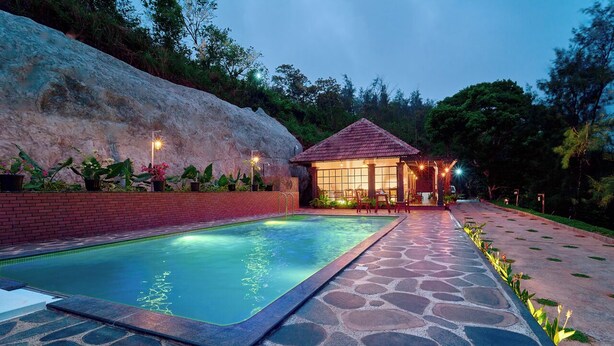 A swimming pool with a stone pathway leading to a gazebo.