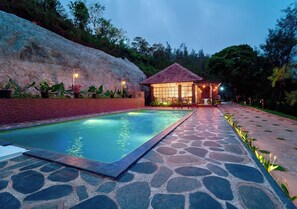 A swimming pool with a stone pathway leading to a gazebo. - Whispering Hills Attappadi by VOYE HOMES (Mannarkkad)