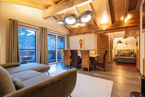 Un salon moderne avec un plafond en bois, un coin repas comprenant une table et des chaises, et un canapé.