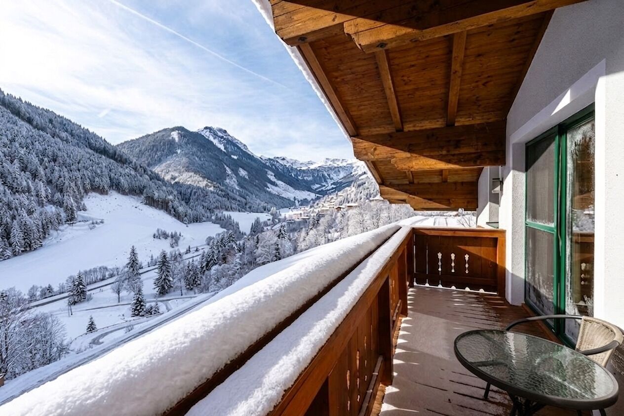 Un balcon offrant une vue sur des montagnes enneigées et un ciel dégagé.