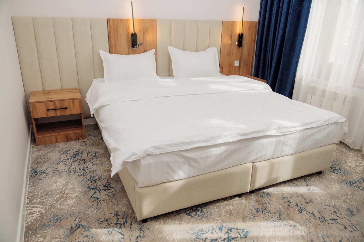 A bed with a wooden headboard, a nightstand, and a blue curtain.