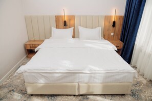 Un lit double avec une tête de lit en bois, deux tables de chevet et un sol à motifs de marbre.