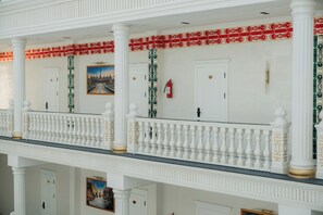 A multi-level building with white columns, a balcony with balustrades, and doors with numbers. - Kampoeng Indonesia Hotel (Khoja Ismail)