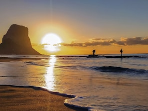 A beach with a large rock formation and the sun setting over the ocean. - Villa Dorada - Plusholidays by Interhome (Calpe/Calp)