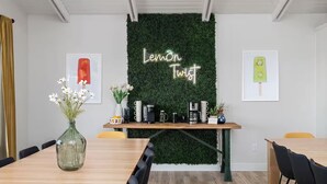Ein Konferenzraum mit grüner Wand, einem Holztisch und einem Neon-Schild mit der Aufschrift 'Lemon Twist'.