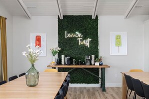 Ein Konferenzraum mit grüner Wand, einem Holztisch und einem Neon-Schild mit der Aufschrift 'Lemon Twist'.