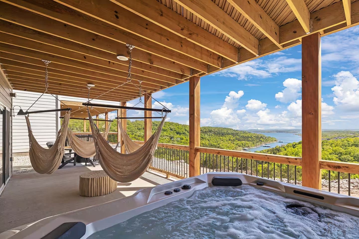 A wooden deck with a hot tub and two hammocks.
