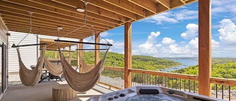 A wooden deck with a hot tub and two hammocks.