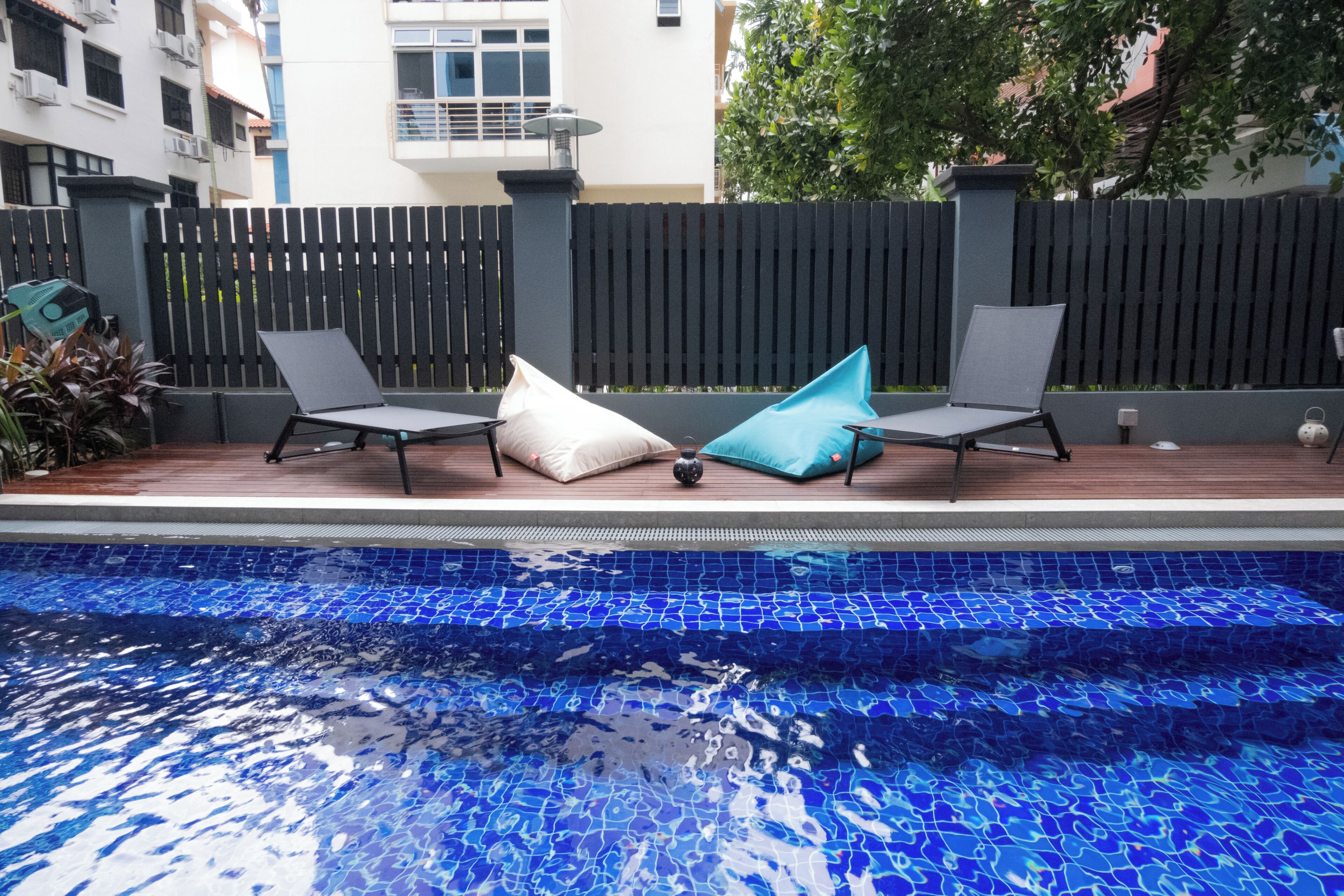 A swimming pool with two lounge chairs and a blue mosaic tile border.