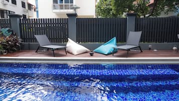 A swimming pool with two lounge chairs and a blue mosaic tile border.