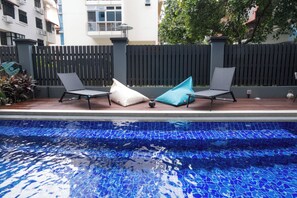 A swimming pool with two lounge chairs and a blue mosaic tile border. - Vichaus Serviced Apartment (Singapore)