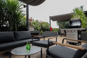 An outdoor seating area with a sofa, chairs, and a round table. - Vichaus Serviced Apartment (Singapore)