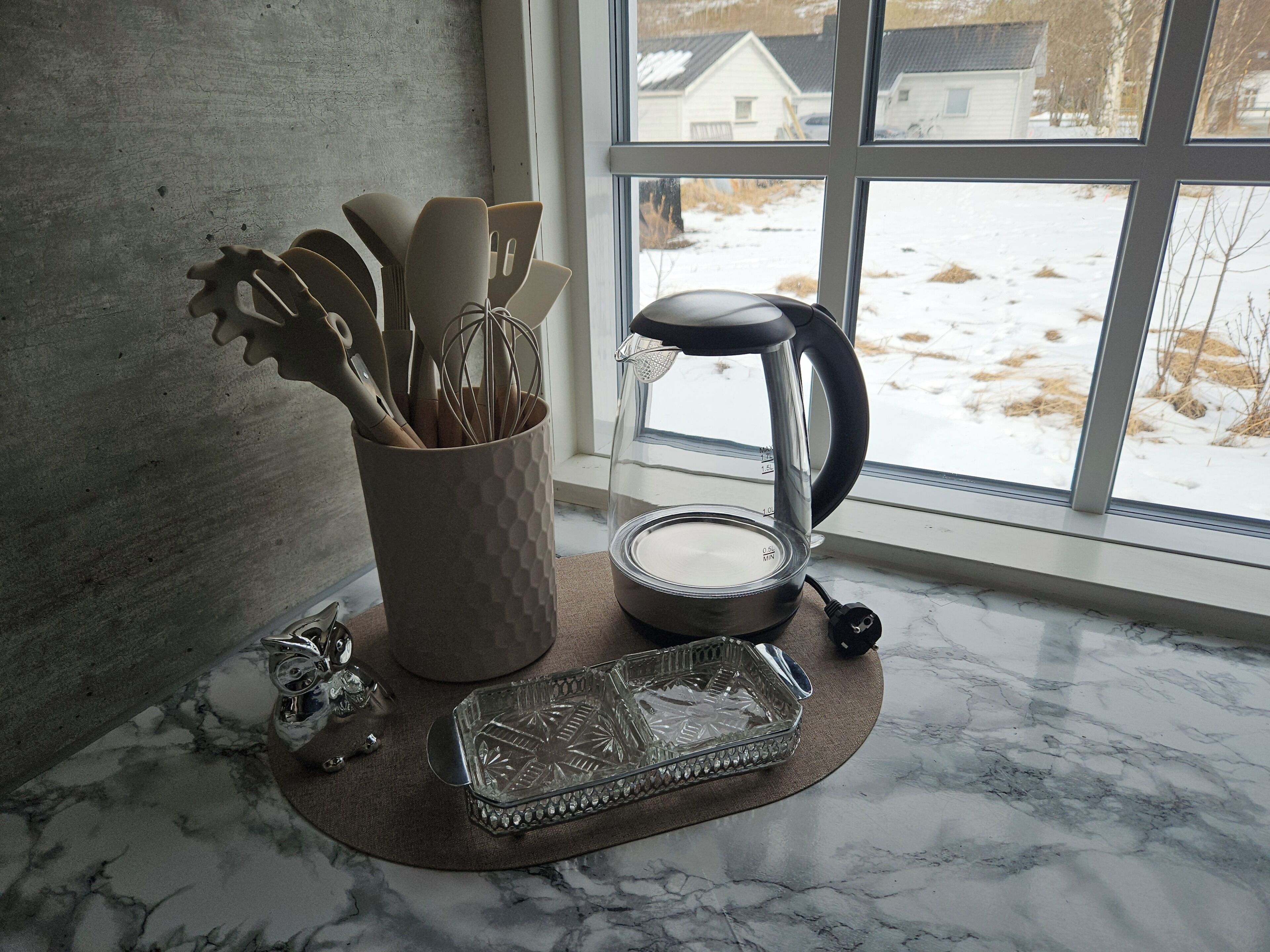 A kitchen counter with a coffee maker, a glass container, and a utensil holder.