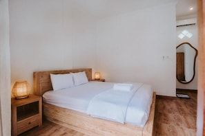 Una cama individual con cabecera de madera, dos lámparas de noche y una mesita de noche con un cajón.