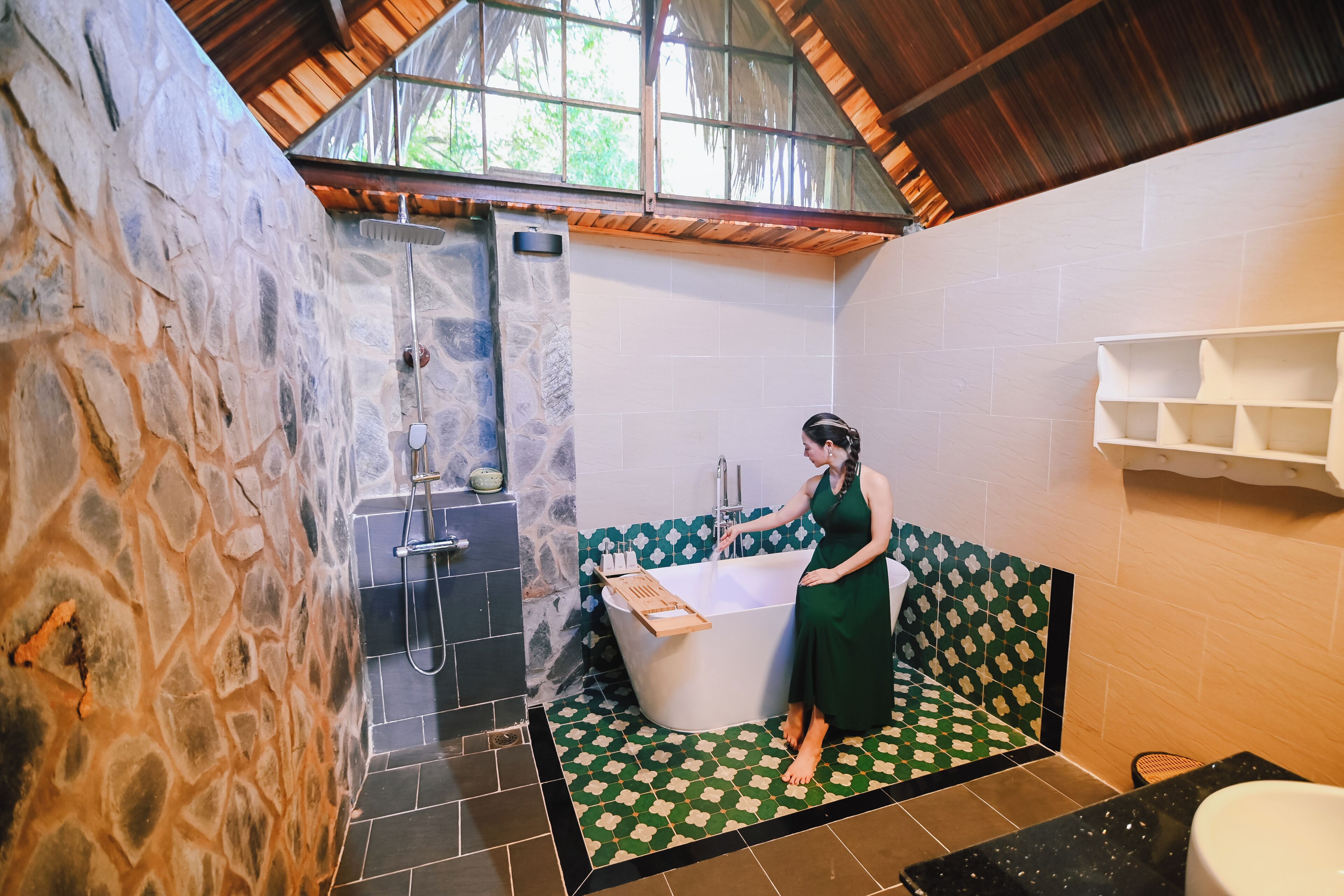 A bathroom with a stone wall, a bathtub, a shower, and a tiled floor.