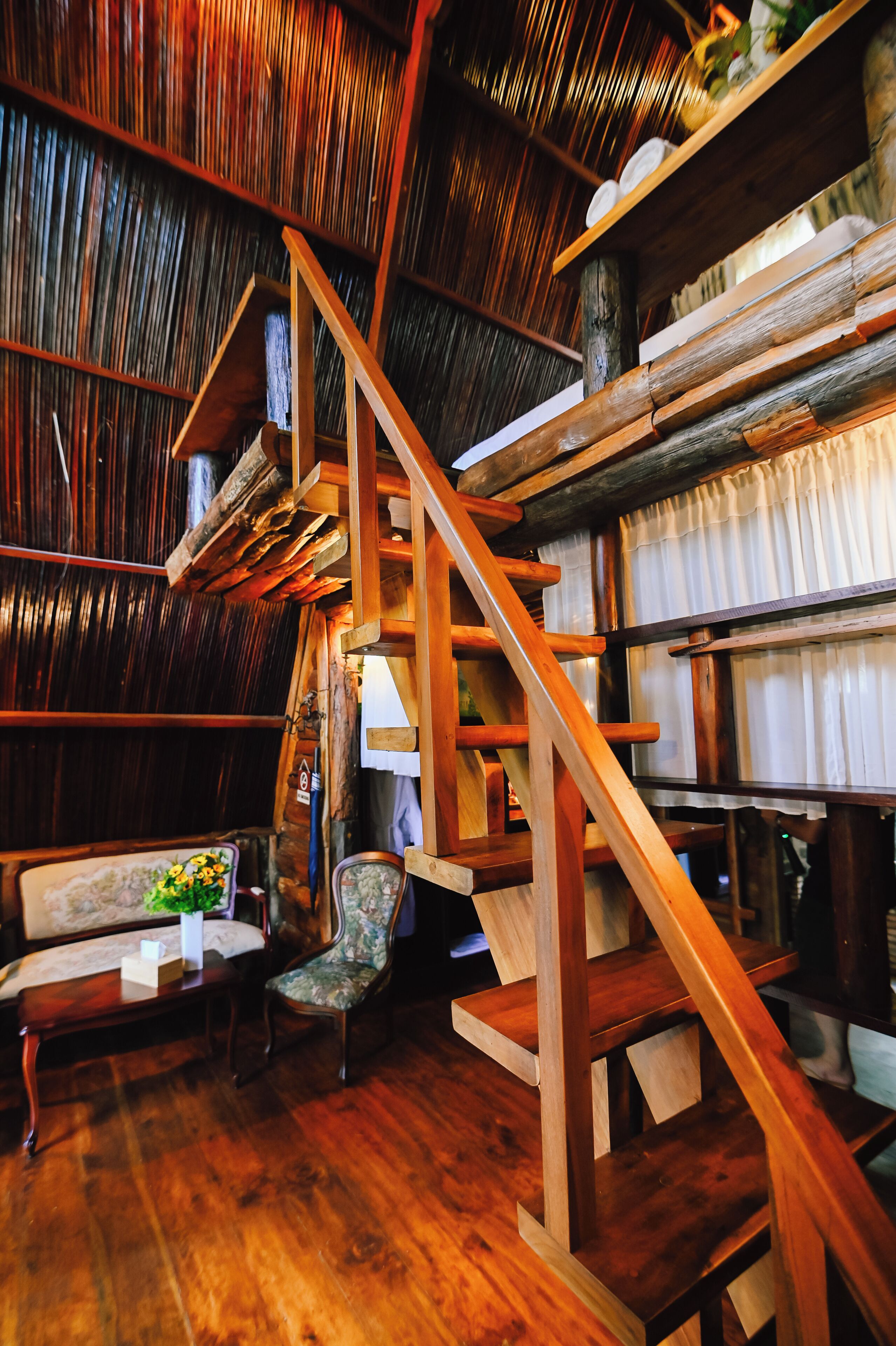 Un interior rústico de madera con una escalera de madera, un banco acolchado y una silla.