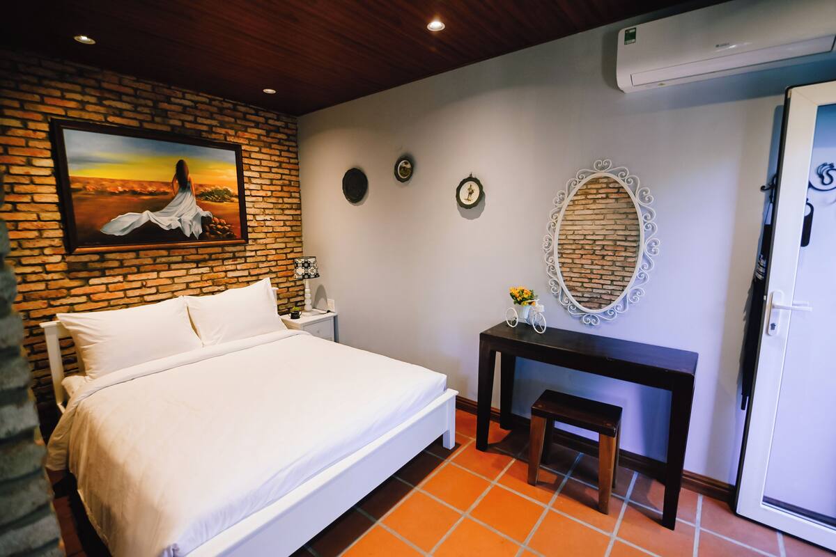 Une chambre d’hôtel avec un lit, un bureau, un miroir et une porte.
