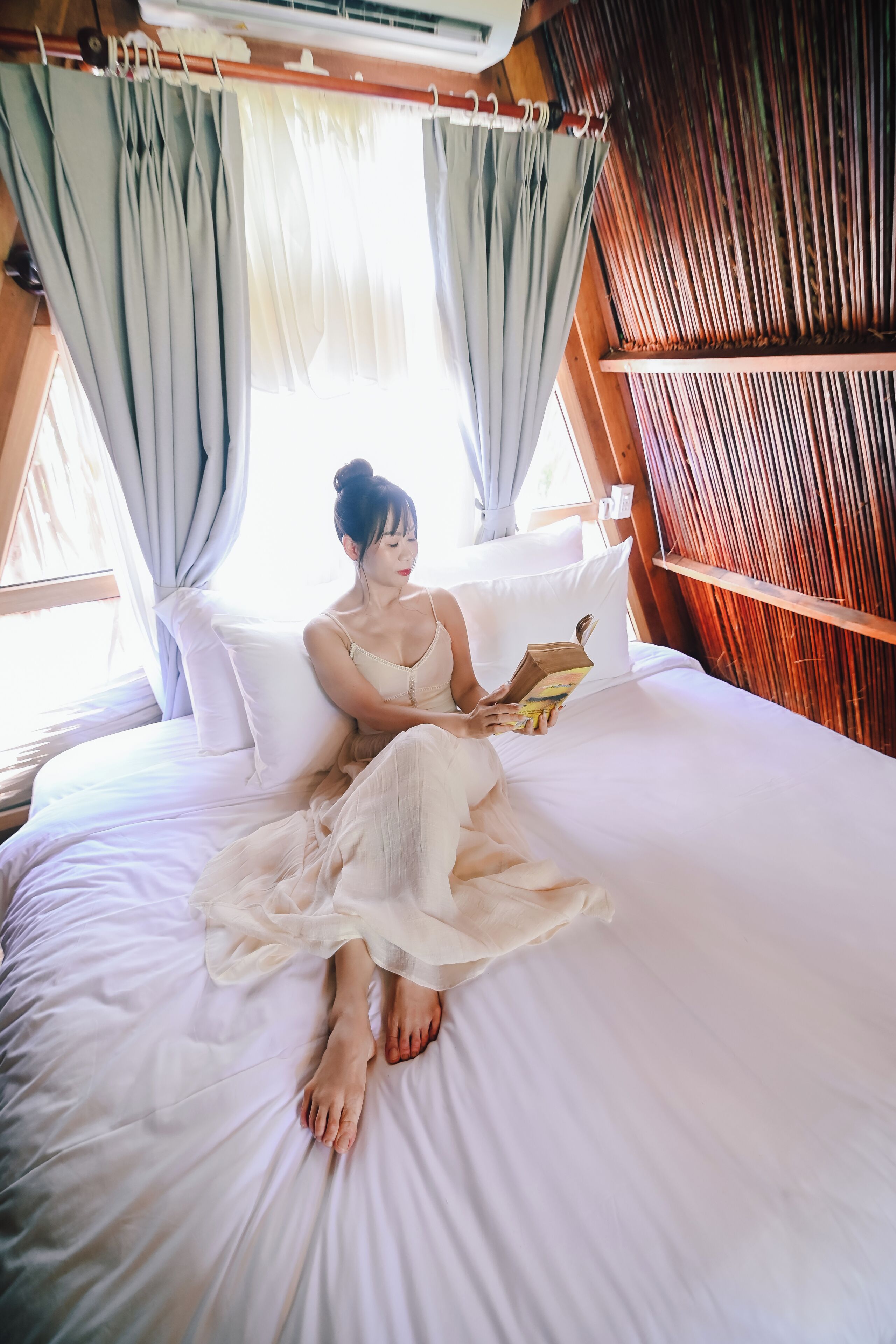Una cama con una persona sentada leyendo un libro.