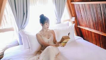 Una cama con una persona sentada leyendo un libro.