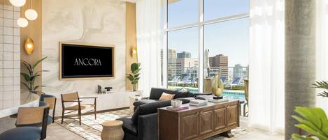 Una sala de estar moderna con un televisor grande, asientos cómodos, un comedor y vistas a un paisaje urbano.