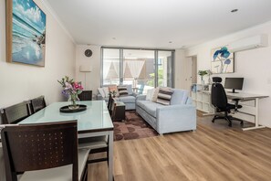 A modern living room with a glass dining table, a sofa, and a desk with a computer. - Merivale stay in South Brisbane two beds two baths one parking (South Brisbane)