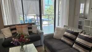 Un salon avec un canapé, une table basse ornée d’un vase de fleurs et une vue sur l’extérieur.