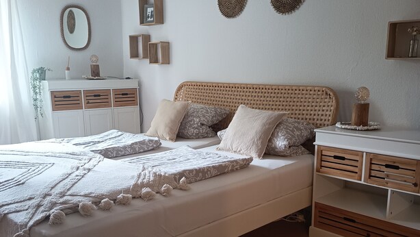 Ein Schlafzimmer mit einem Bett, Nachttischen, einer Kommode und einem Spiegel.