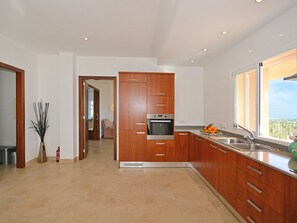 Eine moderne Küche mit Holzschränken, einem eingebauten Backofen und einem großen Fenster.