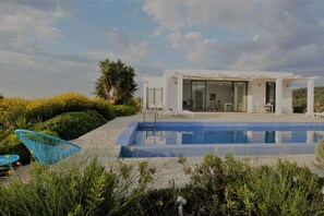 Una casa moderna con piscina, area relax esterna e vista sul paesaggio.