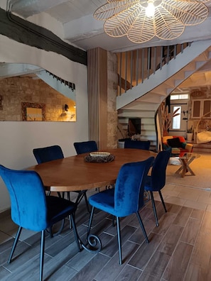 A dining area with a wooden table and blue chairs, a decorative wall, and a staircase leading to another level.