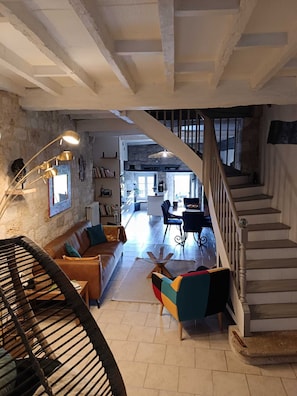 Un vaste espace de vie comprenant un escalier, un coin repas et une cuisine ouverte sur le reste de la piĂšce par une arche.