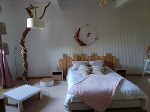 Une chambre à coucher comprenant un lit, une table de chevet, une lampe, un miroir rond et un élément décoratif fixé au mur.