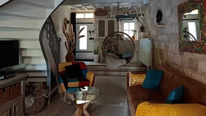 A spacious living area with a staircase, a sofa, a television, and a hanging chair. - Charming 13th-century house in a medieval village in the heart of the Golden Triangle (Cestayrols)