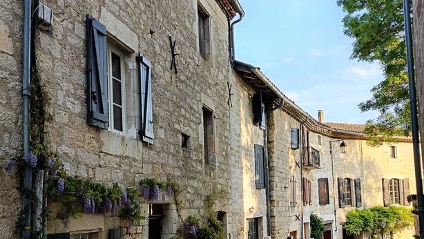A narrow cobblestone street lined with historic stone buildings featuring shuttered windows and balconies. - Charming 13th-century house in a medieval village in the heart of the Golden Triangle (Cestayrols)