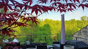 A wooden deck with outdoor furniture, a tall column, and a view of a green landscape. - Charming 13th-century house in a medieval village in the heart of the Golden Triangle (Cestayrols)