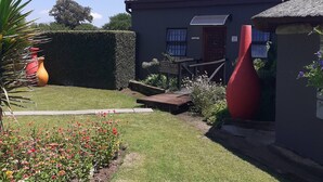 A house with a garden, a wooden deck, and a red sculpture. - Rustic Red Serene & Comfortable Country Home (Benoni)