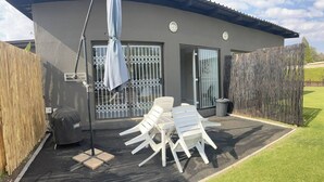 A patio with a table and chairs, a grill, and a covered area with a ceiling fan. - Rustic Red Serene & Comfortable Country Home (Benoni)