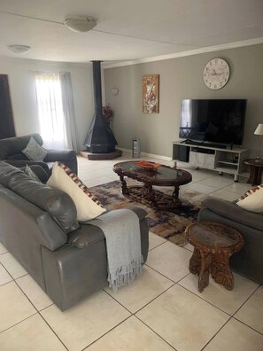 A living room with a sofa, TV, fireplace, and a clock on the wall.