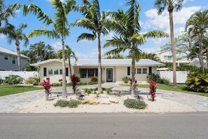 A two-story house with a front porch, palm trees, and a well-maintained lawn. - Island Charm (Holmes Beach)