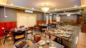 A restaurant with multiple dining tables, chairs, and a chandelier. - Kuku Grand (Gelephu)