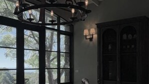 Una habitación con un ventanal grande, un candelabro, un armario y una silla.