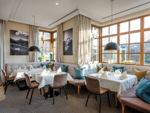 Ein Essbereich mit hohem Tisch und Stühlen, einer Couch und großen Fenstern mit Aussicht.