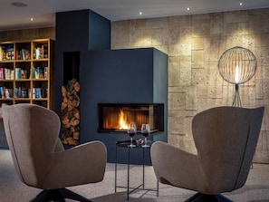 Ein modernes Wohnzimmer mit Kamin, zwei Sesseln, einem Bücherregal und einer außergewöhnlichen Stehlampe.