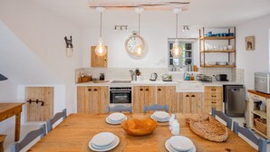 Una cocina moderna con armarios de madera, una isla central, lámparas colgantes y un reloj en la pared.