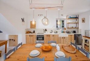 Eine moderne Küche mit Holzschränken, einer zentralen Kücheninsel, hängenden Pendelleuchten und einer Uhr an der Wand.