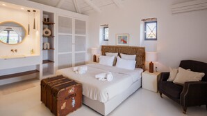 Un dormitorio con una cama grande, mesitas de noche, un armario y una maleta.